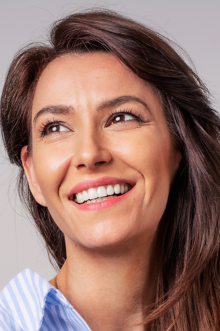 A woman smiling warmly, radiating confidence and self-care.