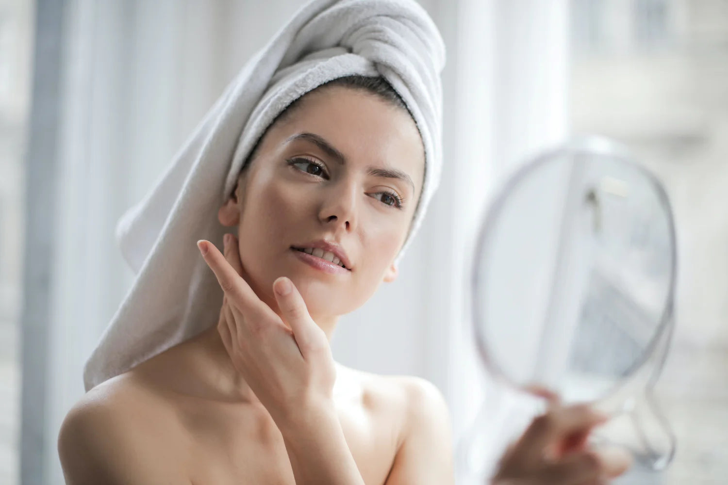 woman examining her skin in the mirror post-skin injectables